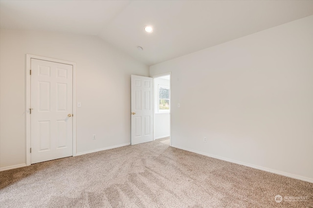 empty room featuring carpet floors and vaulted ceiling