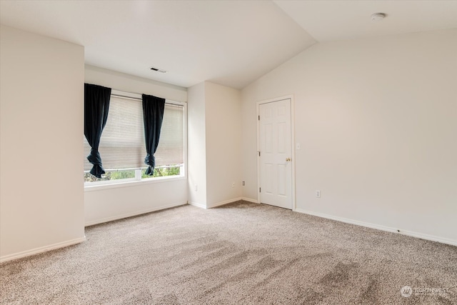 carpeted spare room featuring vaulted ceiling