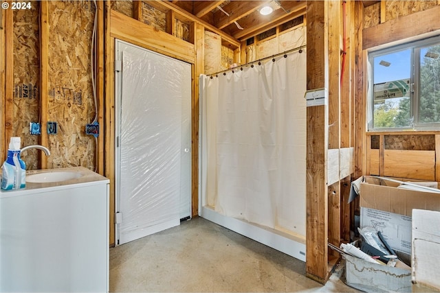 bathroom with a shower with shower curtain, concrete floors, and sink