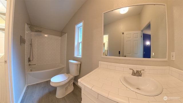 full bathroom with vanity, lofted ceiling, tiled shower / bath combo, wood-type flooring, and toilet