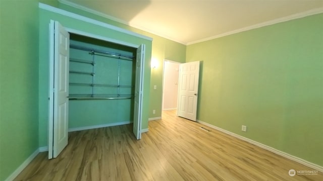 unfurnished bedroom featuring wood-type flooring, a closet, and crown molding