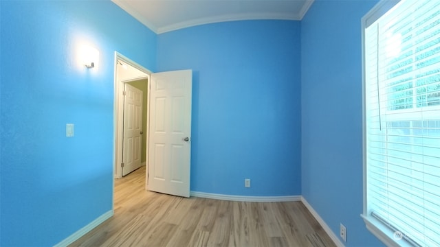 spare room featuring light wood-type flooring and crown molding