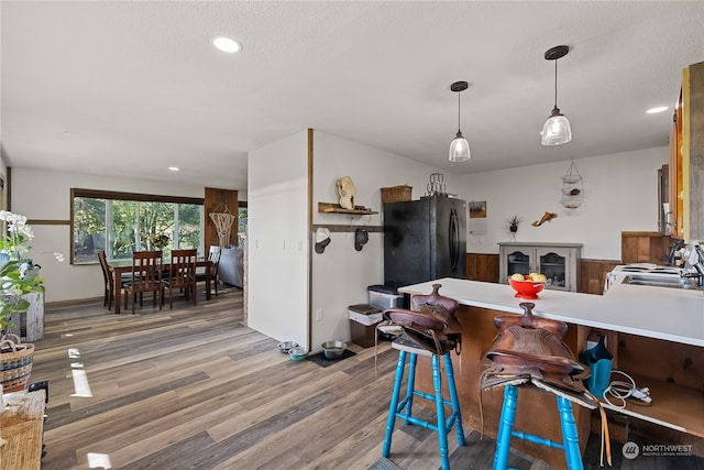 kitchen featuring range, kitchen peninsula, wood-type flooring, sink, and black fridge