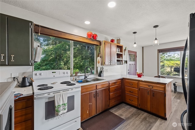 kitchen with pendant lighting, sink, kitchen peninsula, white electric range, and hardwood / wood-style flooring