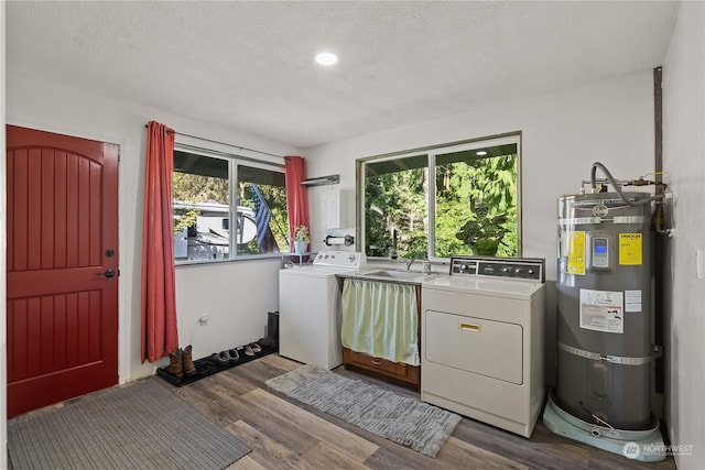 laundry room with strapped water heater, hardwood / wood-style flooring, a healthy amount of sunlight, and washing machine and dryer