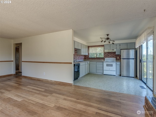 kitchen featuring stainless steel fridge, backsplash, black dishwasher, white stove, and sink