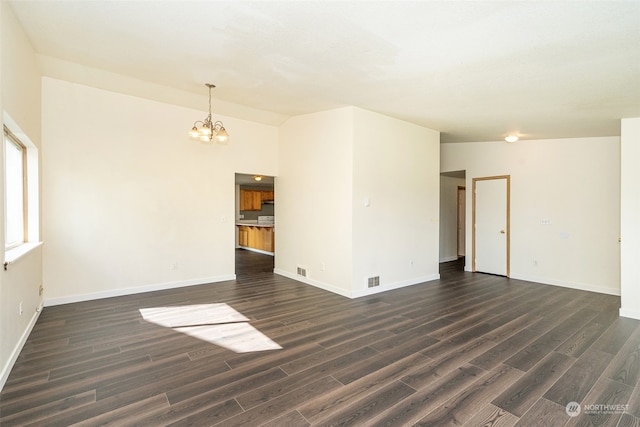 spare room with an inviting chandelier, dark wood-type flooring, and high vaulted ceiling