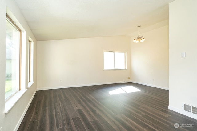 unfurnished room with a notable chandelier, dark hardwood / wood-style floors, and vaulted ceiling