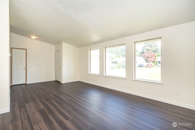 spare room with vaulted ceiling and dark wood-type flooring