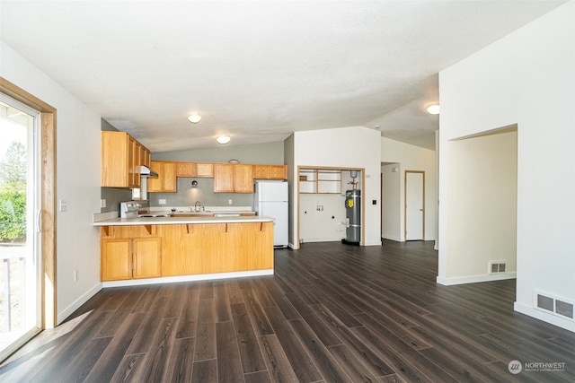 kitchen featuring lofted ceiling, kitchen peninsula, white appliances, a kitchen breakfast bar, and dark hardwood / wood-style floors