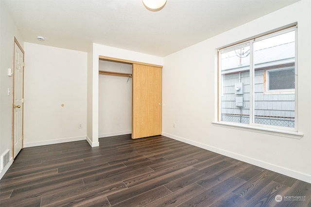 unfurnished bedroom featuring dark hardwood / wood-style floors and a closet