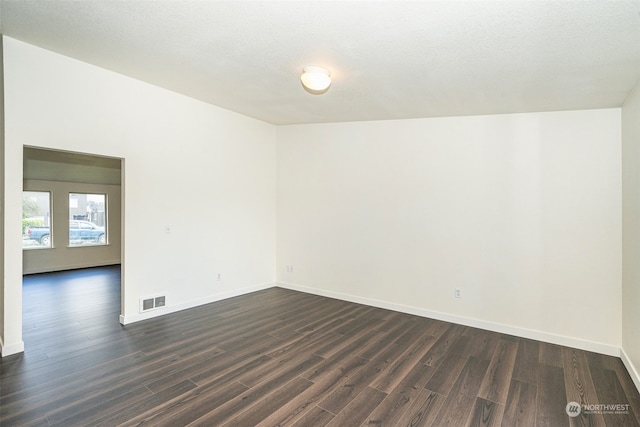 empty room featuring a textured ceiling, lofted ceiling, and dark hardwood / wood-style floors