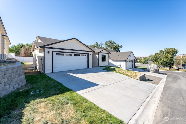 view of front of home with cooling unit, a garage, and a front lawn