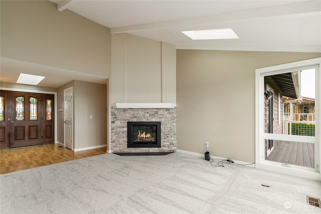 unfurnished living room featuring carpet, a fireplace, and lofted ceiling with skylight