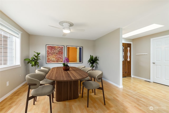 dining space featuring light hardwood / wood-style floors, a skylight, and ceiling fan