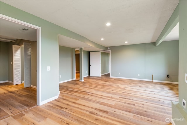 unfurnished room featuring light hardwood / wood-style floors and beamed ceiling