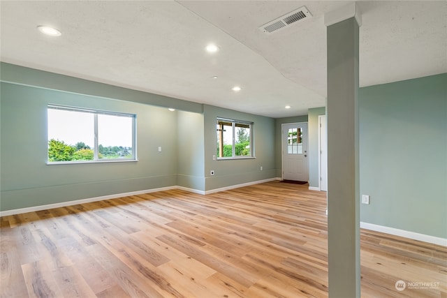 unfurnished room with a textured ceiling and light hardwood / wood-style flooring