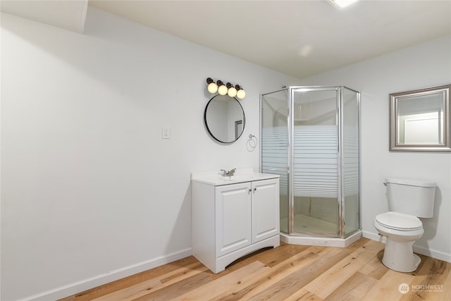 bathroom with hardwood / wood-style flooring, walk in shower, vanity, and toilet