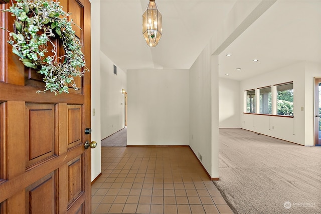 carpeted entryway with a notable chandelier