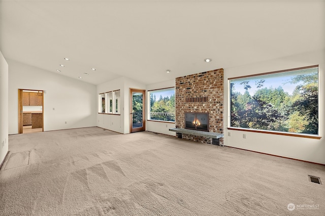 unfurnished living room with vaulted ceiling, light carpet, and a brick fireplace