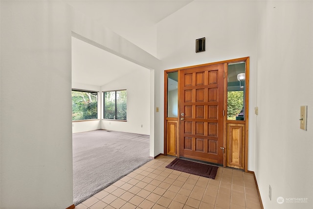 foyer entrance with light carpet and vaulted ceiling