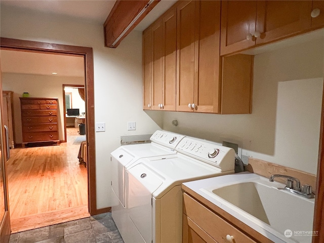 laundry area with cabinets, dark hardwood / wood-style floors, washing machine and clothes dryer, and sink