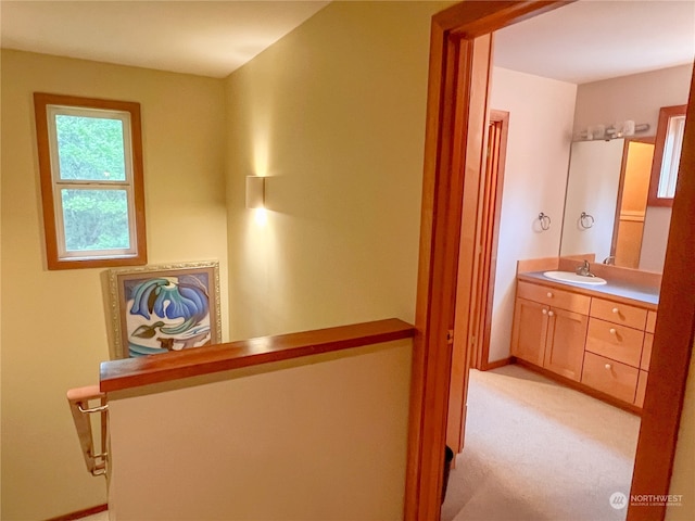 hall featuring light colored carpet and sink