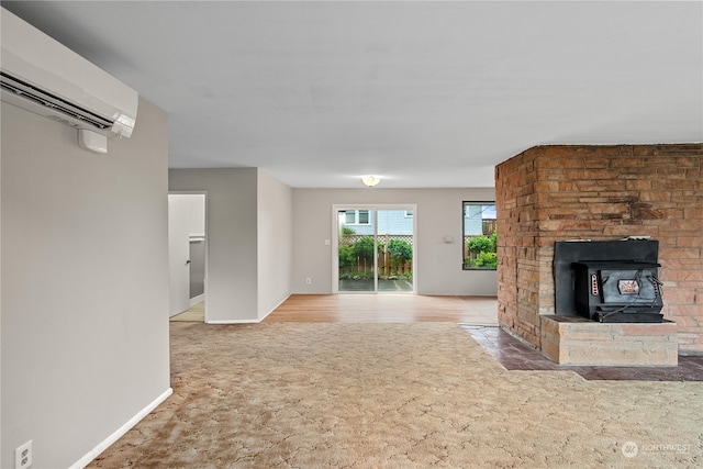 unfurnished living room featuring light hardwood / wood-style floors, a fireplace, a wood stove, and a wall mounted air conditioner