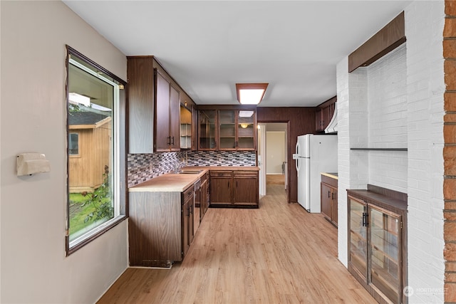 kitchen featuring white refrigerator, tasteful backsplash, a fireplace, light wood-type flooring, and sink