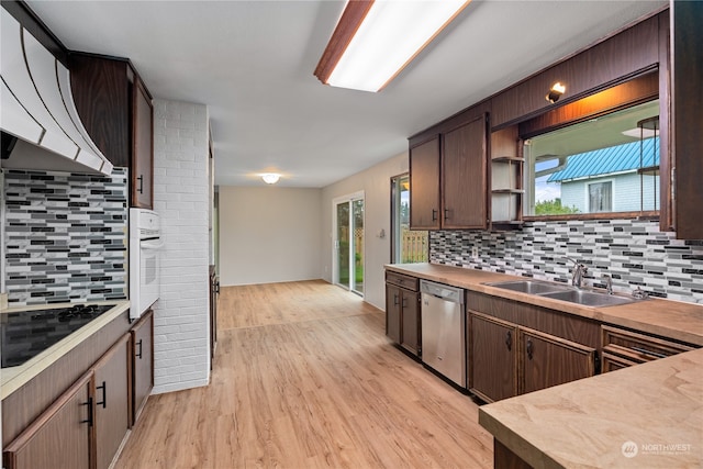 kitchen featuring sink, tasteful backsplash, stainless steel dishwasher, light wood-type flooring, and a healthy amount of sunlight