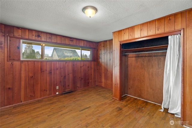 unfurnished bedroom with wood walls, a closet, and dark hardwood / wood-style floors