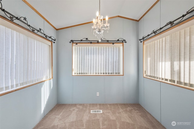 carpeted empty room featuring a notable chandelier, vaulted ceiling, and ornamental molding