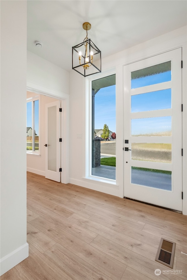 doorway to outside with light hardwood / wood-style floors and an inviting chandelier