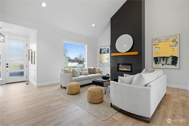 living room featuring light hardwood / wood-style floors, a fireplace, and high vaulted ceiling