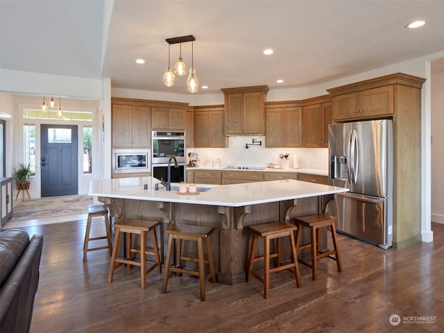 kitchen featuring appliances with stainless steel finishes, a large island, dark wood-type flooring, and a notable chandelier