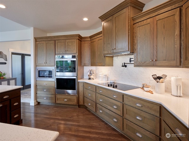 kitchen featuring decorative backsplash, appliances with stainless steel finishes, and dark hardwood / wood-style floors