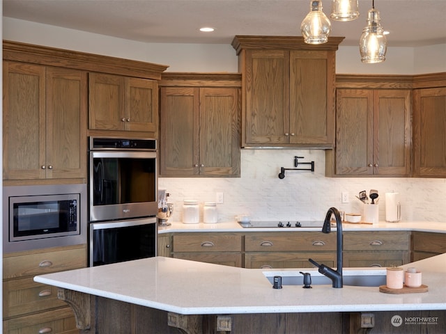 kitchen with hanging light fixtures, sink, tasteful backsplash, appliances with stainless steel finishes, and a breakfast bar area