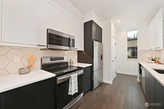 kitchen with sink, white cabinetry, decorative backsplash, appliances with stainless steel finishes, and dark hardwood / wood-style flooring