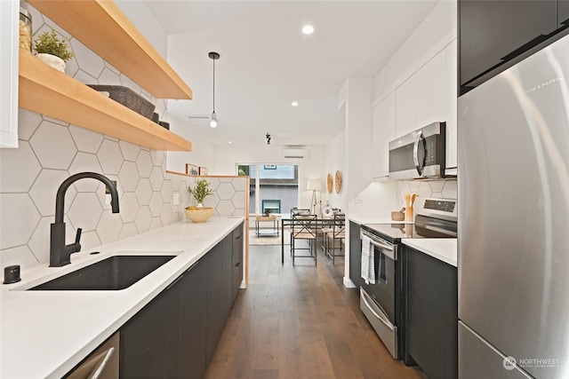 kitchen with sink, decorative light fixtures, white cabinetry, appliances with stainless steel finishes, and dark hardwood / wood-style floors