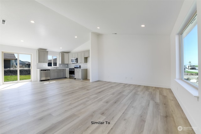 unfurnished living room with light wood-type flooring and high vaulted ceiling