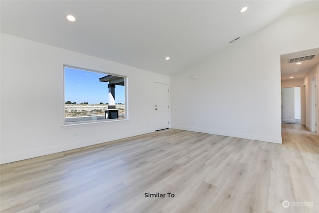 spare room with light hardwood / wood-style floors and vaulted ceiling