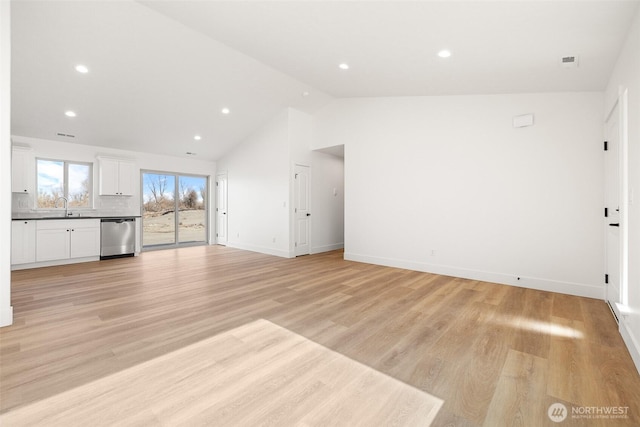 unfurnished living room with baseboards, vaulted ceiling, light wood-style floors, a sink, and recessed lighting