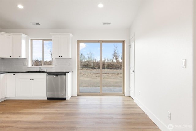 kitchen featuring dishwasher, backsplash, a sink, and visible vents