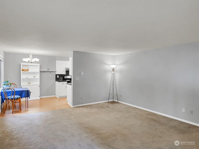 unfurnished living room featuring light carpet and a notable chandelier