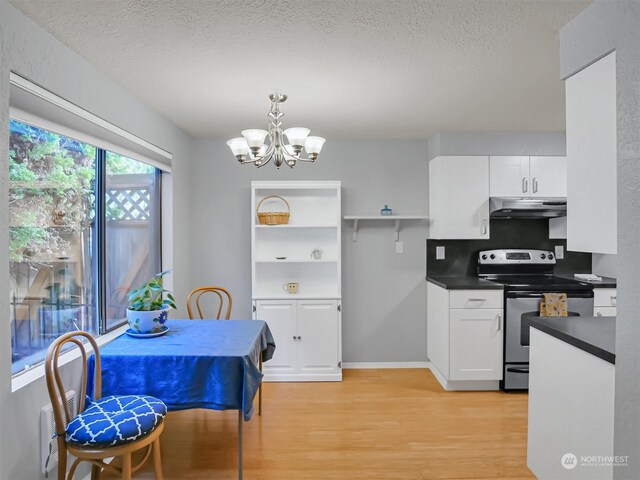 kitchen featuring pendant lighting, electric range, a notable chandelier, light hardwood / wood-style floors, and white cabinetry