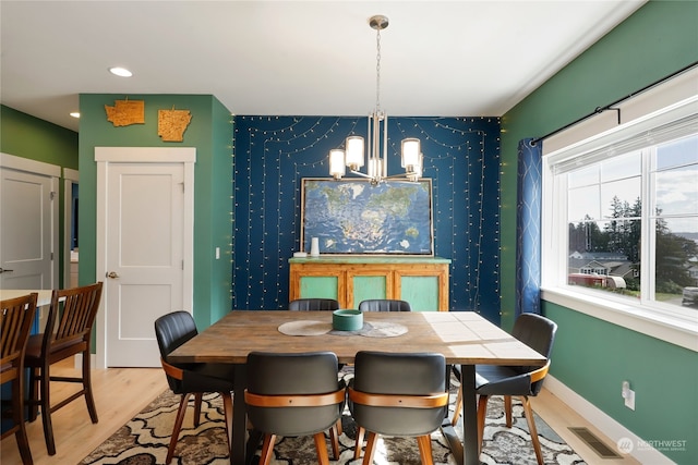 dining area with light hardwood / wood-style floors and a notable chandelier