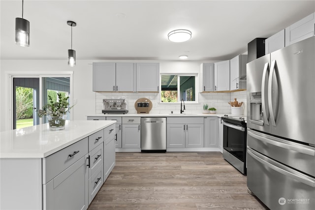 kitchen with appliances with stainless steel finishes, a healthy amount of sunlight, light hardwood / wood-style floors, and sink