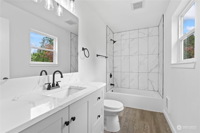 full bathroom with tiled shower / bath combo, vanity, toilet, and hardwood / wood-style flooring