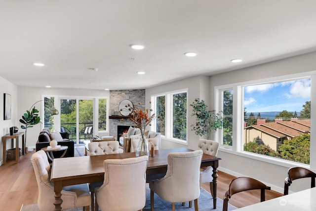 dining space featuring light hardwood / wood-style floors and a stone fireplace