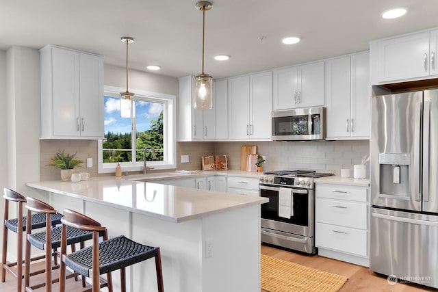 kitchen with kitchen peninsula, pendant lighting, stainless steel appliances, and white cabinets